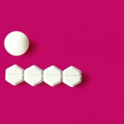 magenta background with one round white tablet and four hexagonal white tablets beneath